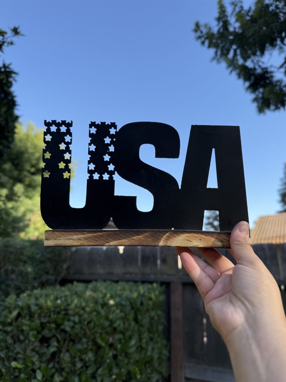 A steel USA sign with a star-cut flag, mounted on a wood base.