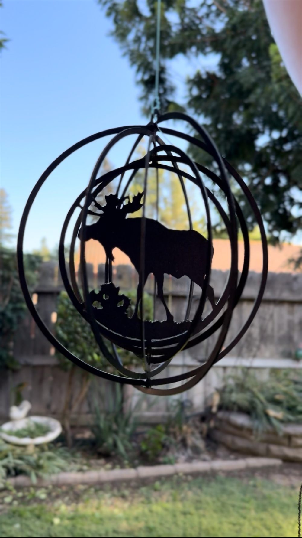 A steel moose wind spinner turning inside a metal sphere.