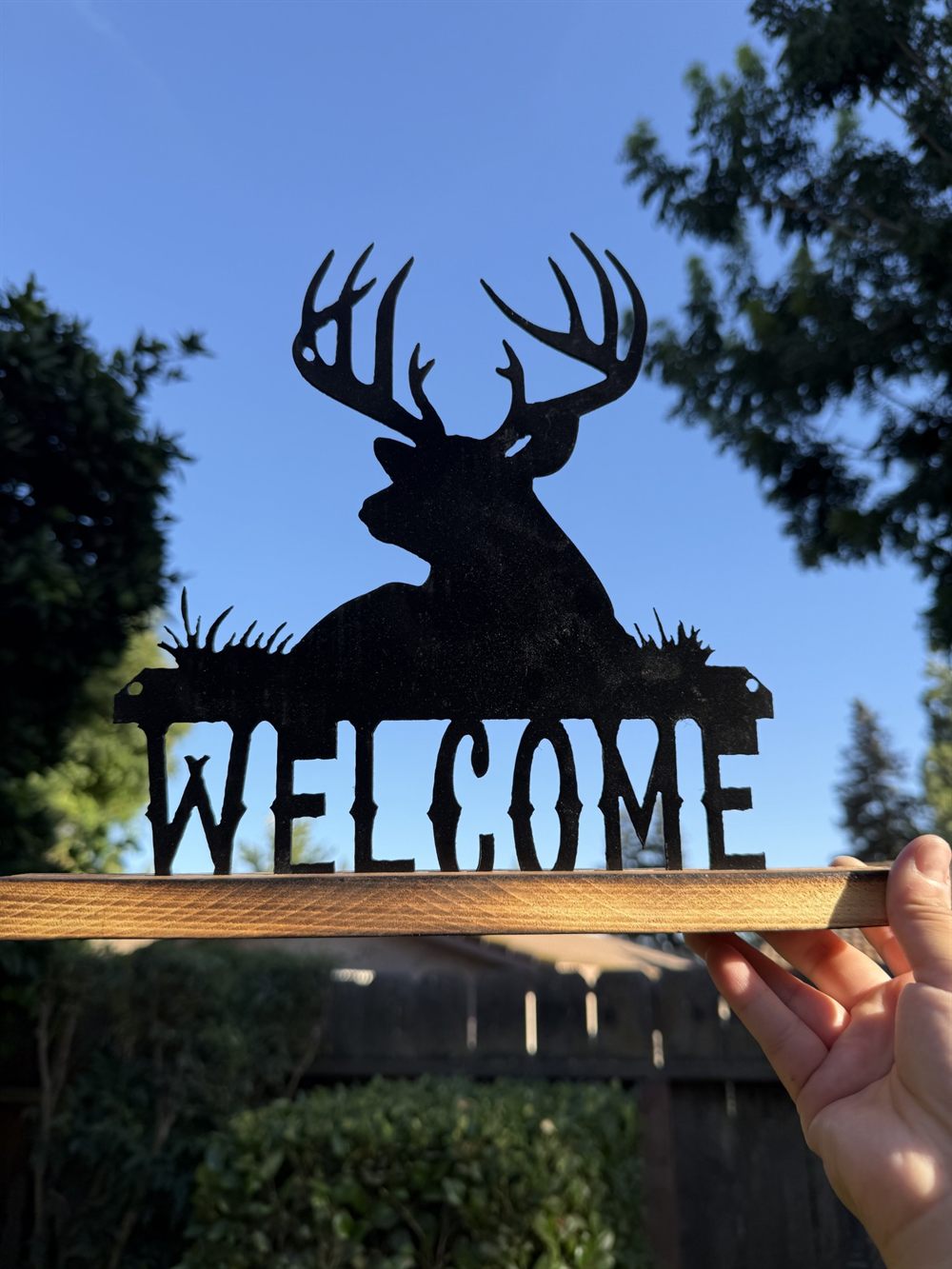 A steel Welcome sign with a buck and pine tree.