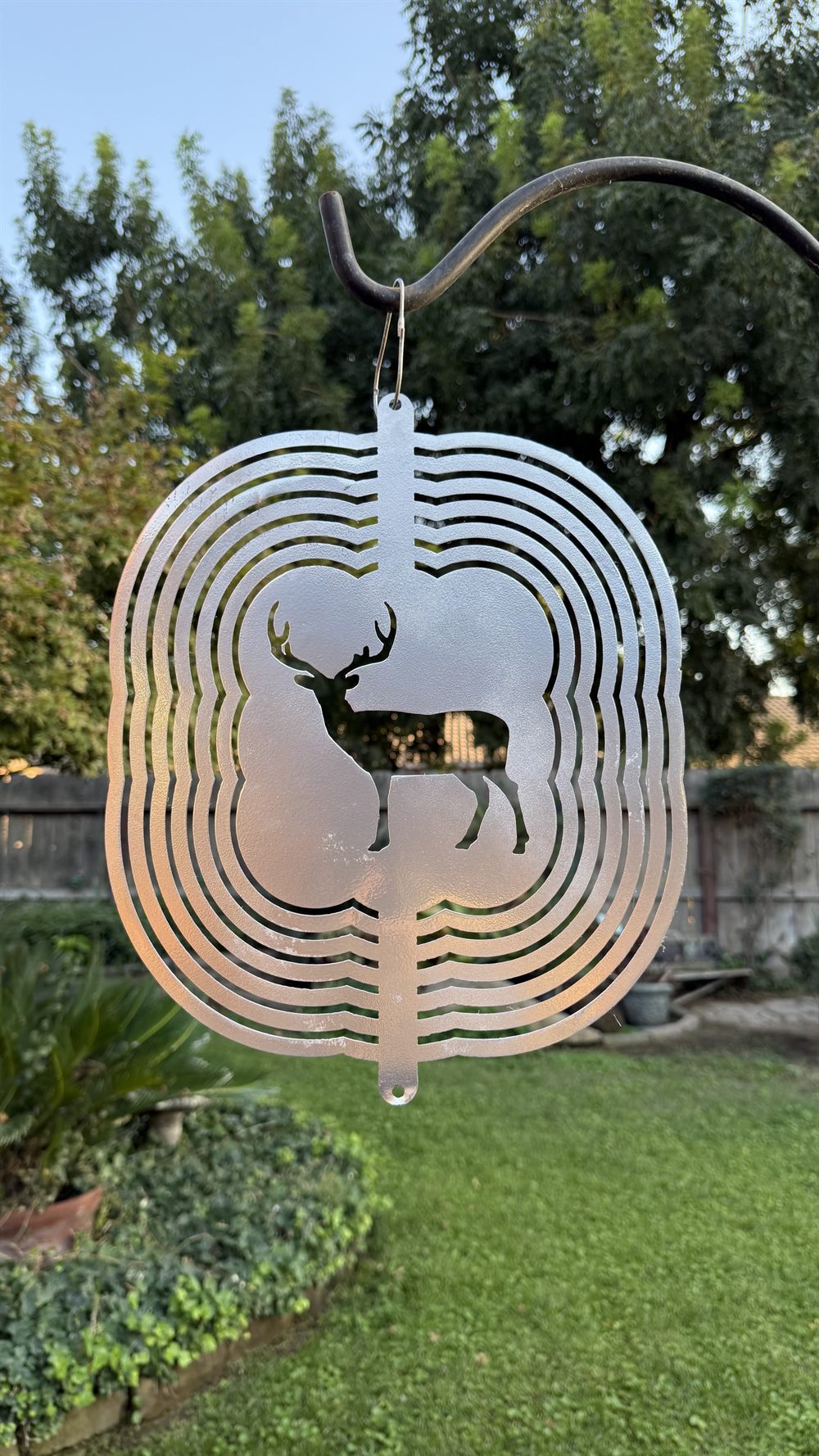 A steel deer wind spinner inside a spinning sphere.